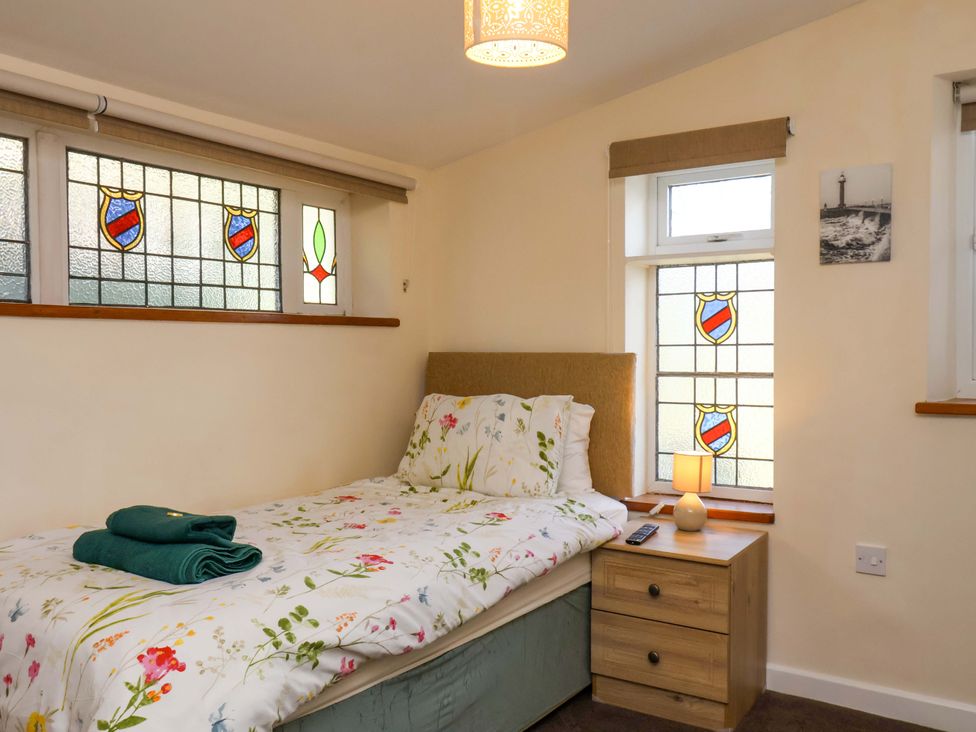 A bedroom with a bed and stained glass windows at The Nook in Robin Hood’s Bay