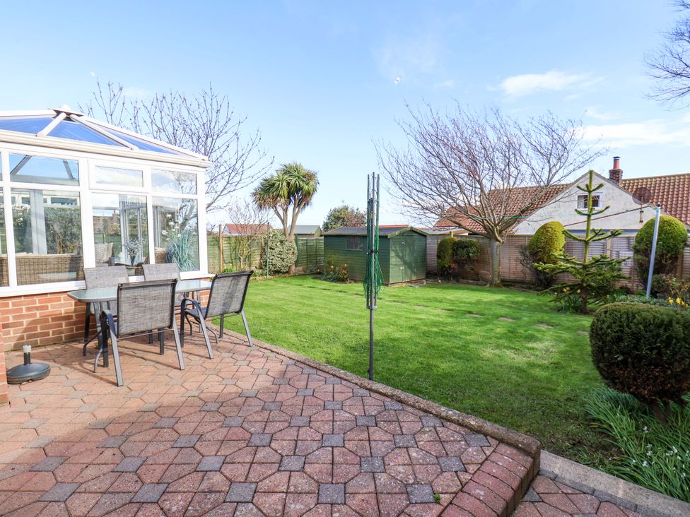 A garden with a conservatory and seating area at The Nook in Robin Hood’s Bay