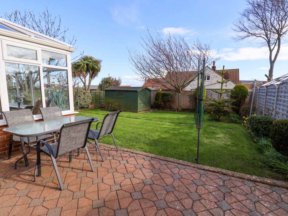 A garden with a table and chairs and a shed at The Nook in Robin Hood’s Bay