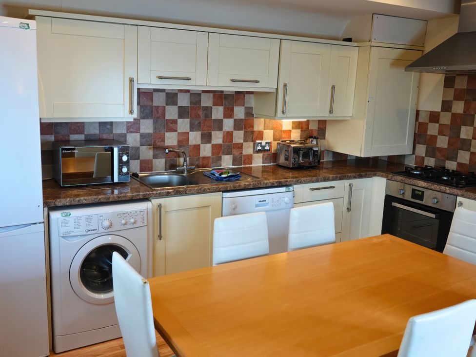 A kitchen with appliances and a dining table at Bracken Lodge in Finlakes Holiday Park near Chudleigh
