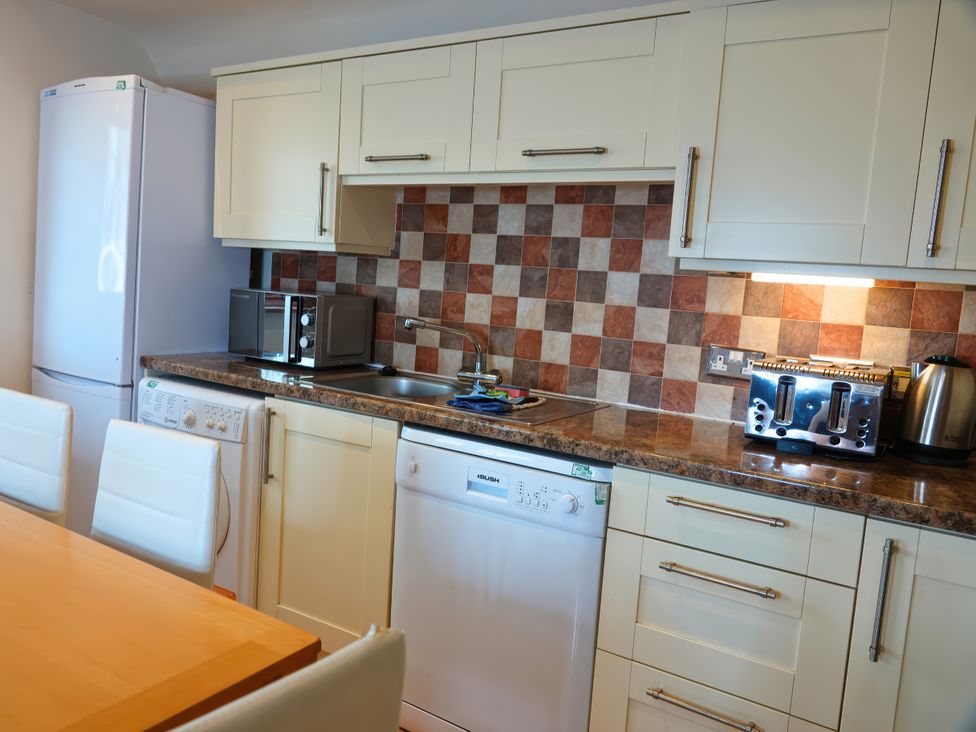 A kitchen with appliances and a dining table at Bracken Lodge Finlakes Holiday Park near Chudleigh