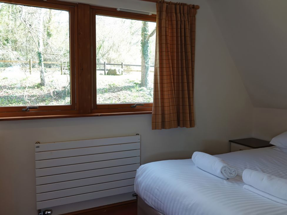 A bedroom with a bed and a window at Bracken Lodge Finlakes Holiday Park near Chudleigh
