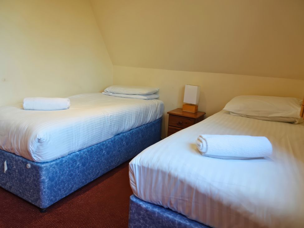 A bedroom with two beds and a bedside table at Bracken Lodge Finlakes Holiday Park near Chudleigh