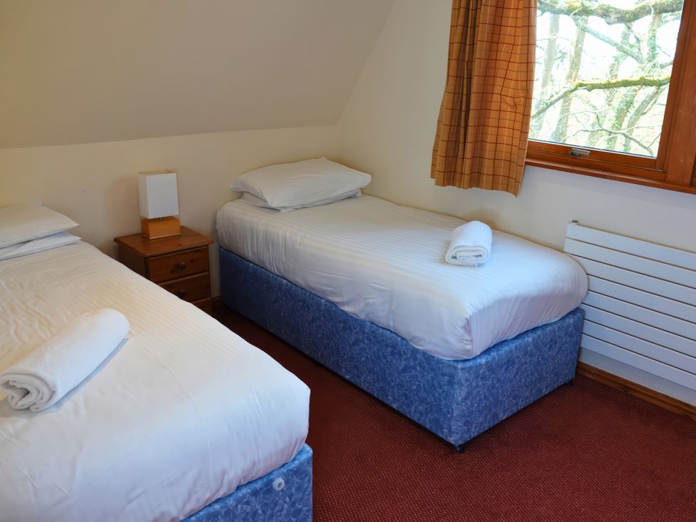 A bedroom with two single beds and a window at Bracken Lodge Finlakes Holiday Park near Chudleigh