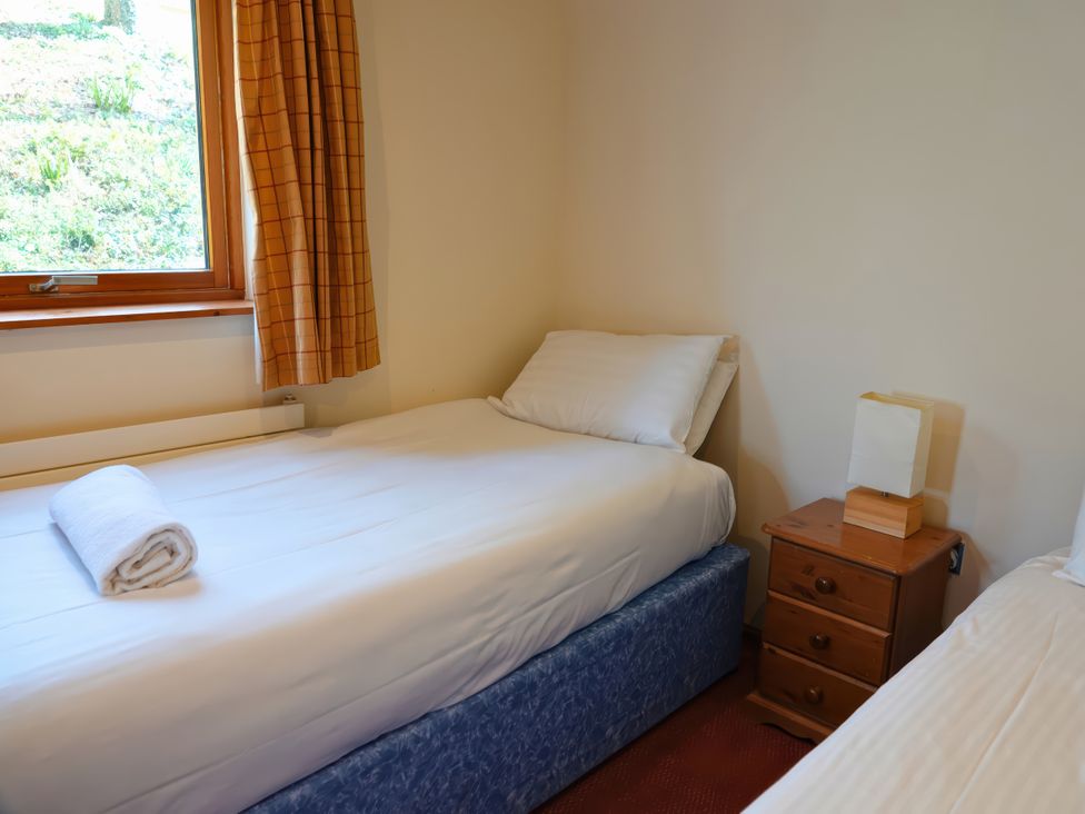 A bedroom with two beds and a bedside table at Bracken Lodge Finlakes Holiday Park near Chudleigh
