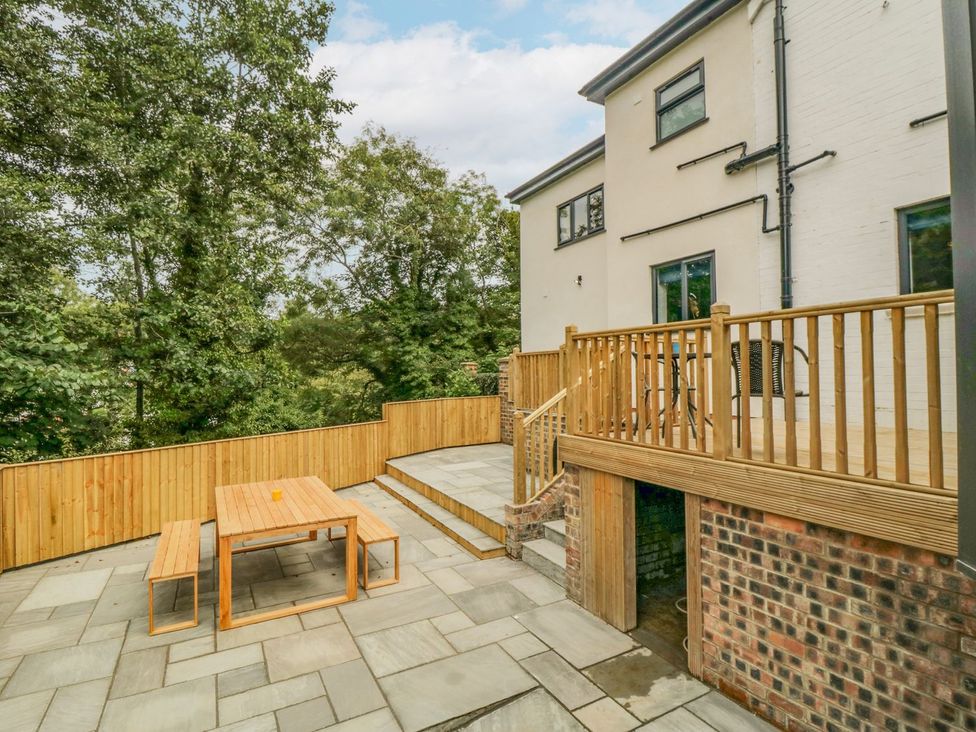 A patio area with wooden furniture at Riverside House in Scarborough