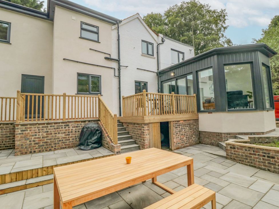 An outdoor area with a wooden table and glass conservatory at Riverside House in Scarborough
