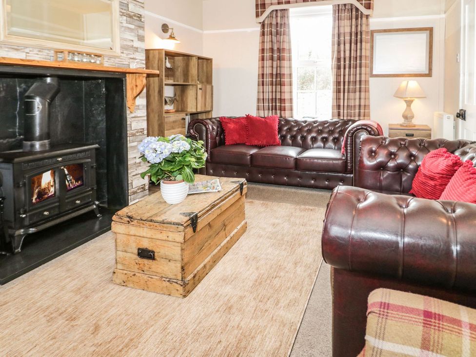 A living room with a sofa, coffee table and fireplace at 2 Old Coastguard House in Beaumaris