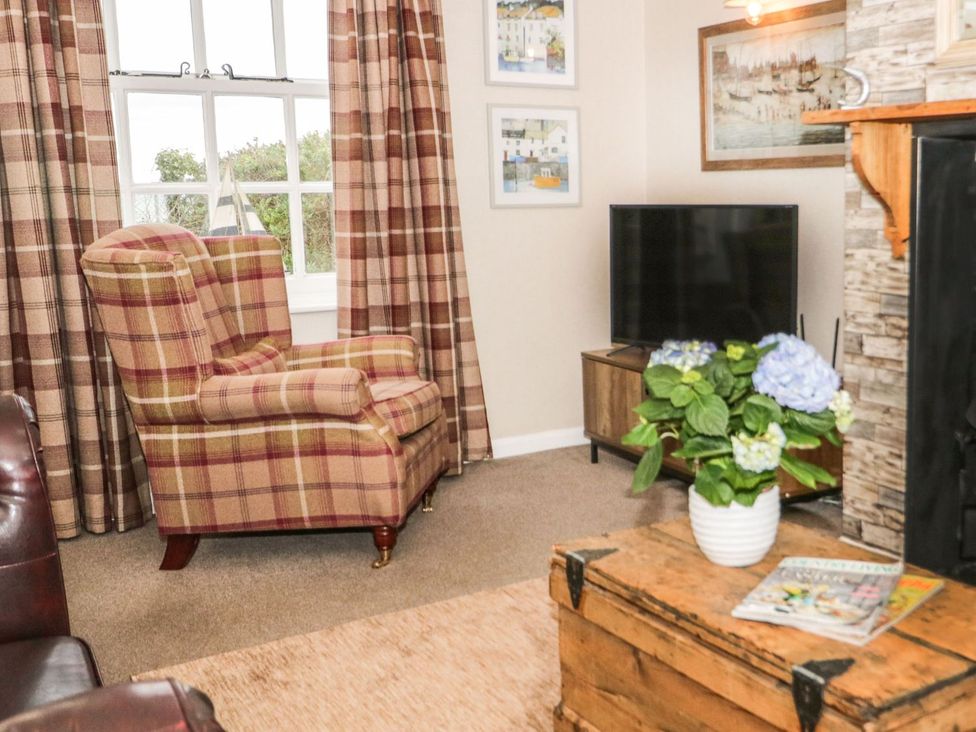 A living room with an armchair and a television at 2 Old Coastguard House Beaumaris