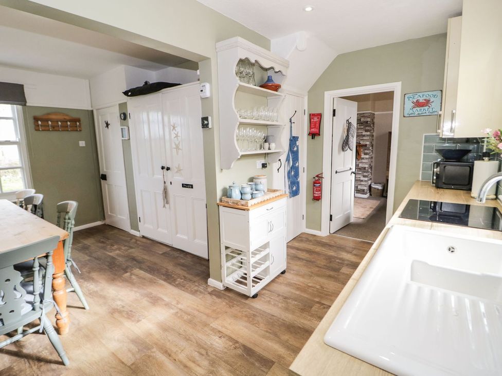 A kitchen with a table and chairs at 2 Old Coastguard House Beaumaris
