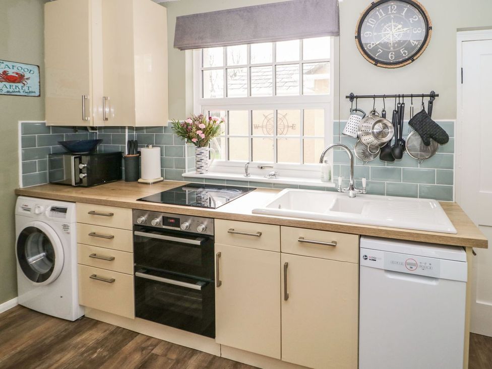 A kitchen with appliances including a washing machine and oven at 2 Old Coastguard House Beaumaris