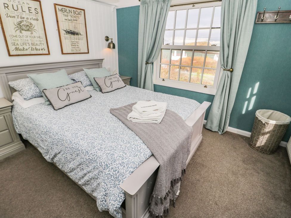 A bedroom with a bed, pillows, and window at 2 Old Coastguard House, Beaumaris