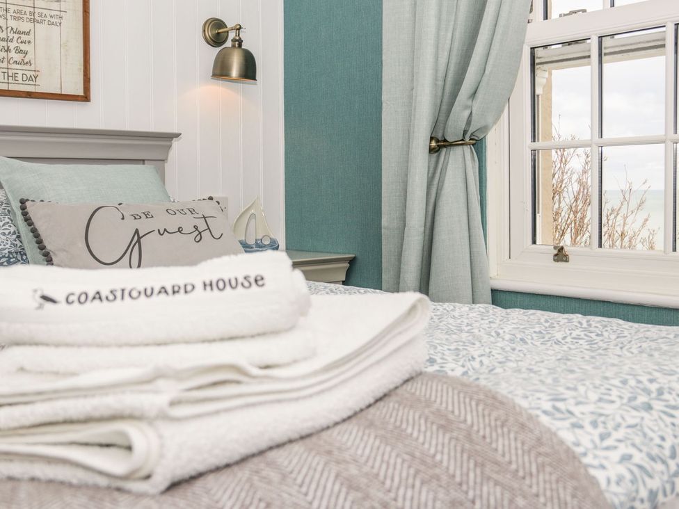 A bedroom with bedding, pillows, and a window at 2 Old Coastguard House Beaumaris