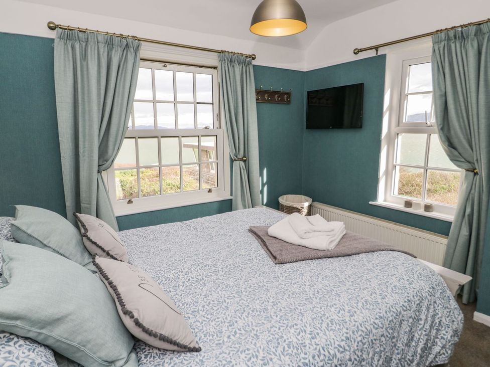 A bedroom with a bed and television at 2 Old Coastguard House Beaumaris