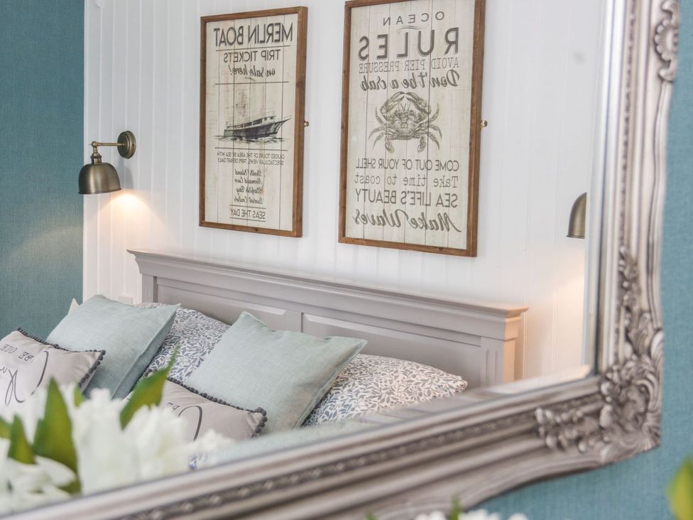 A bedroom with a bed and decorative elements at 2 Old Coastguard House, Beaumaris