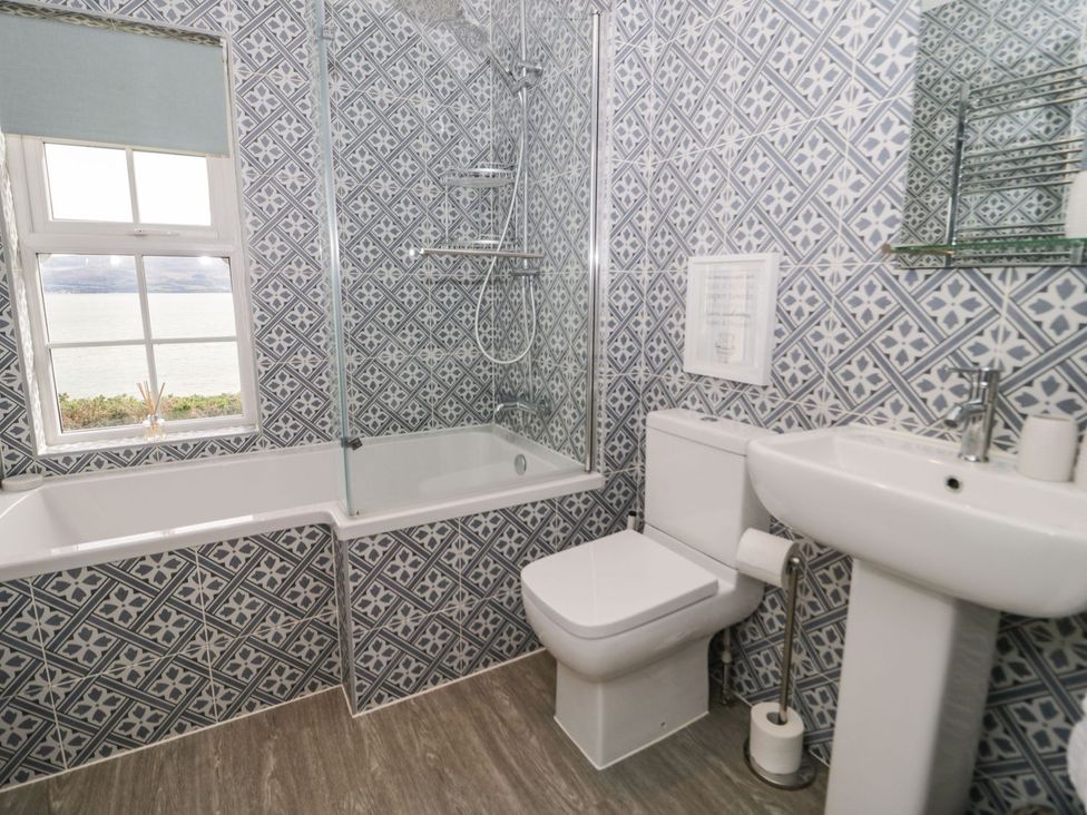 A bathroom with a bathtub, shower, toilet, and sink at 2 Old Coastguard House Beaumaris