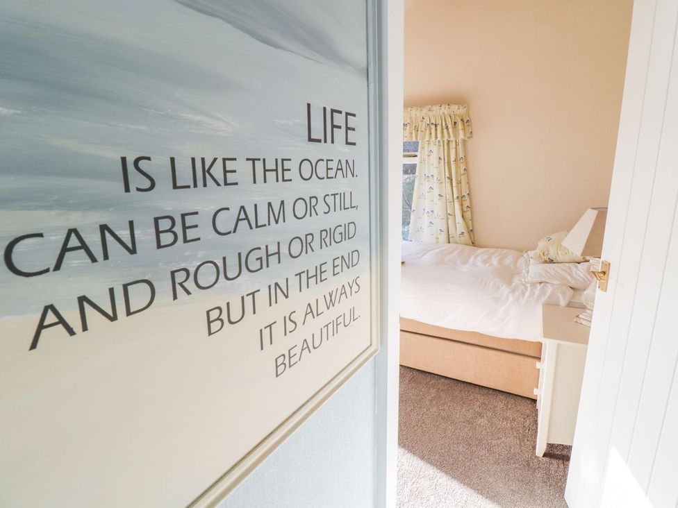 A bedroom with a visible bed and curtain at 2 Old Coastguard House Beaumaris