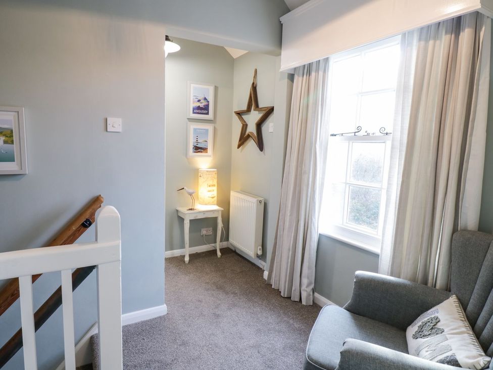 A landing with a staircase and an armchair at 2 Old Coastguard House Beaumaris