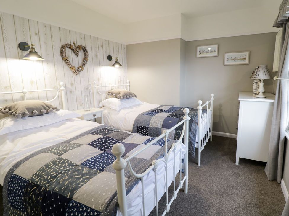 A bedroom with two beds and a bedside table at 2 Old Coastguard House in Beaumaris