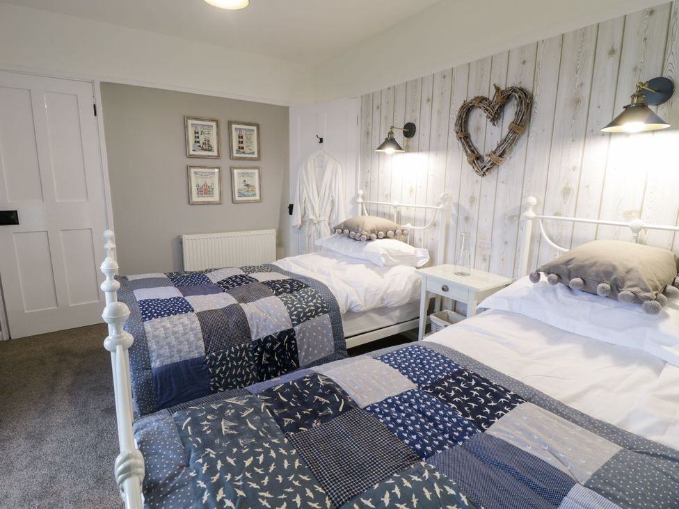 A bedroom with two beds and wall art at 2 Old Coastguard House Beaumaris
