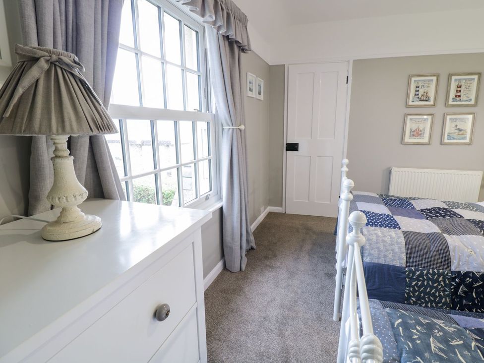 A bedroom with a lamp window and two beds at 2 Old Coastguard House in Beaumaris