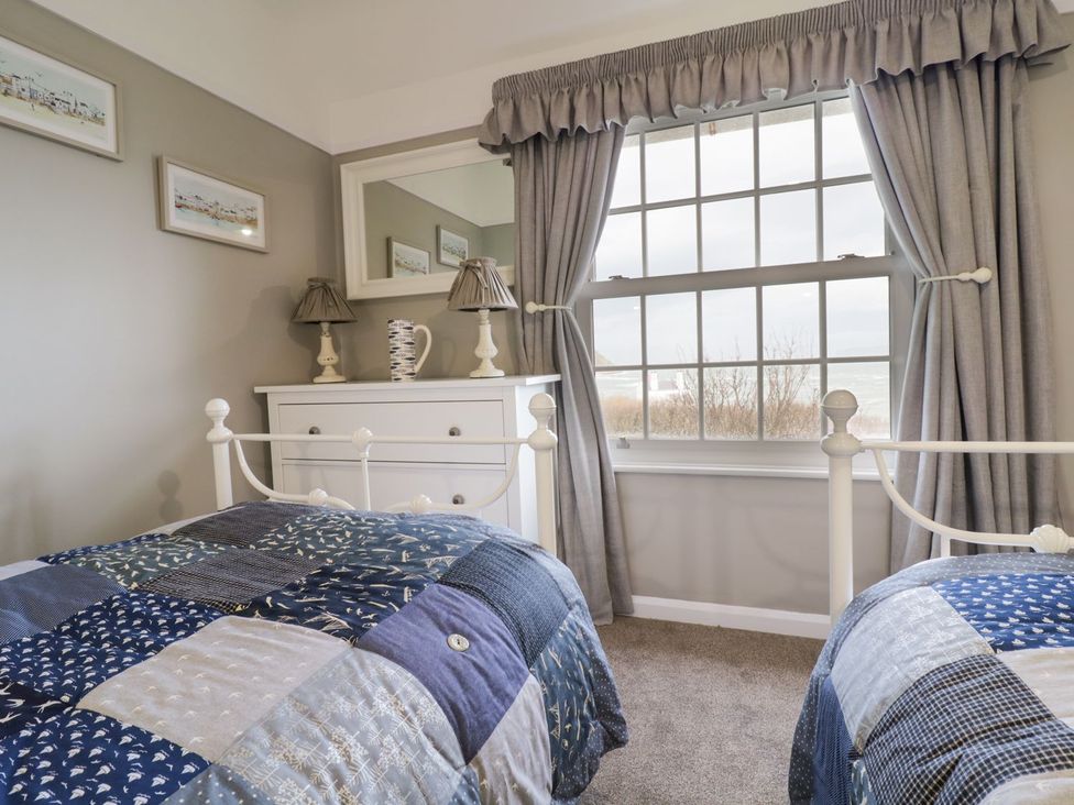 A bedroom with two beds and a dresser at 2 Old Coastguard House in Beaumaris