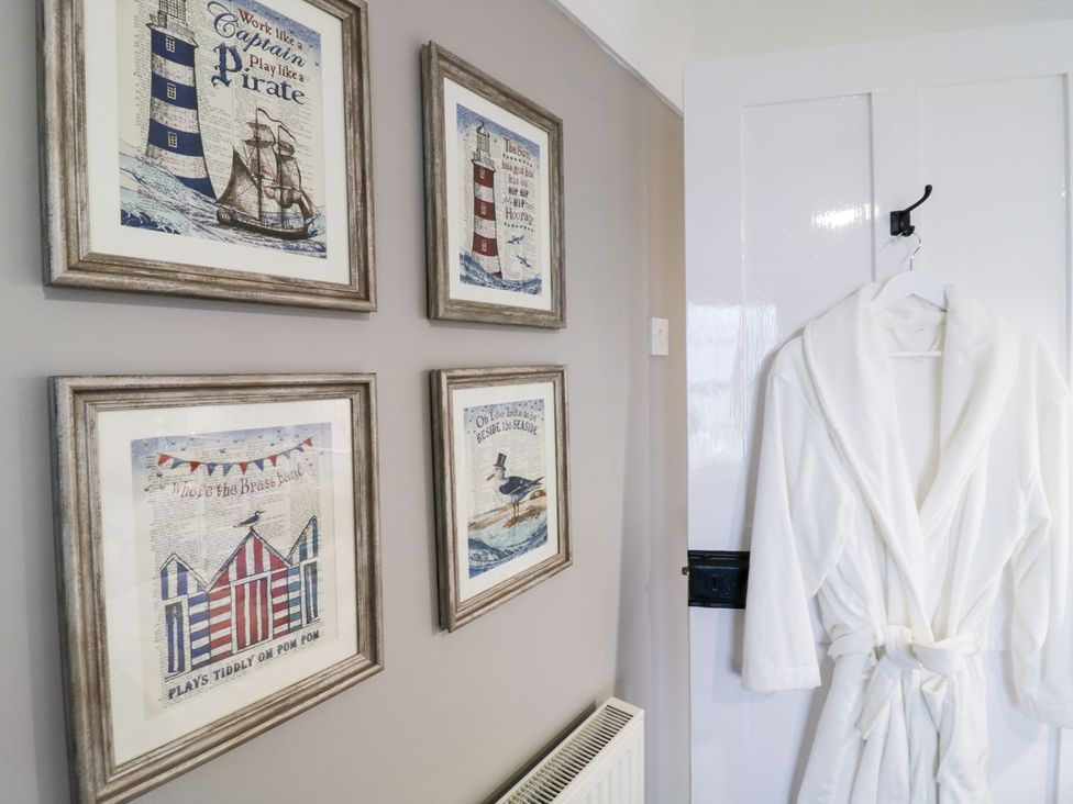 A bathroom with framed artwork and a white bathrobe at 2 Old Coastguard House Beaumaris