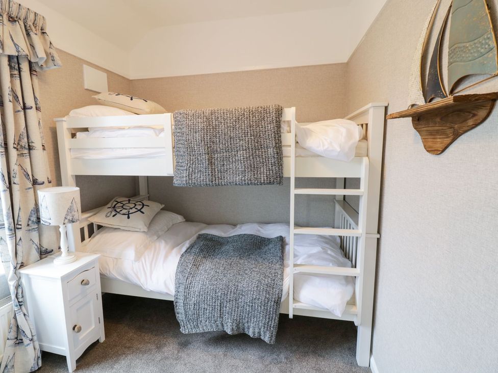 A bedroom with a bunk bed and bedside table at 2 Old Coastguard House Beaumaris