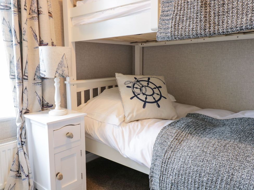 A bedroom with a bunk bed and nightstand at 2 Old Coastguard House Beaumaris