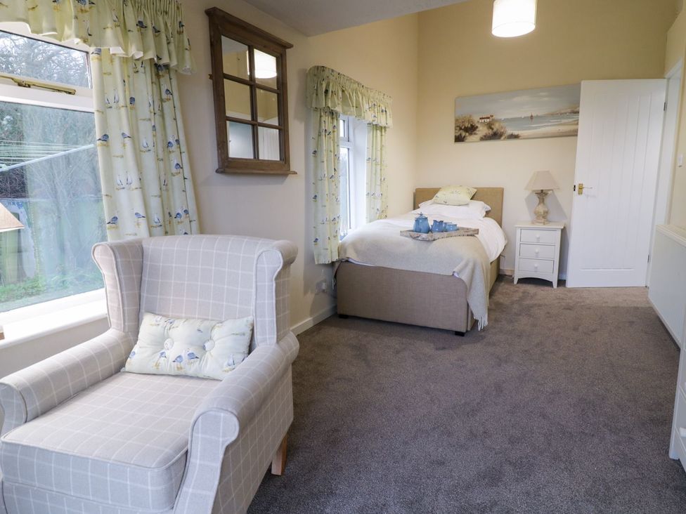 A bedroom with a bed and armchair at 2 Old Coastguard House Beaumaris