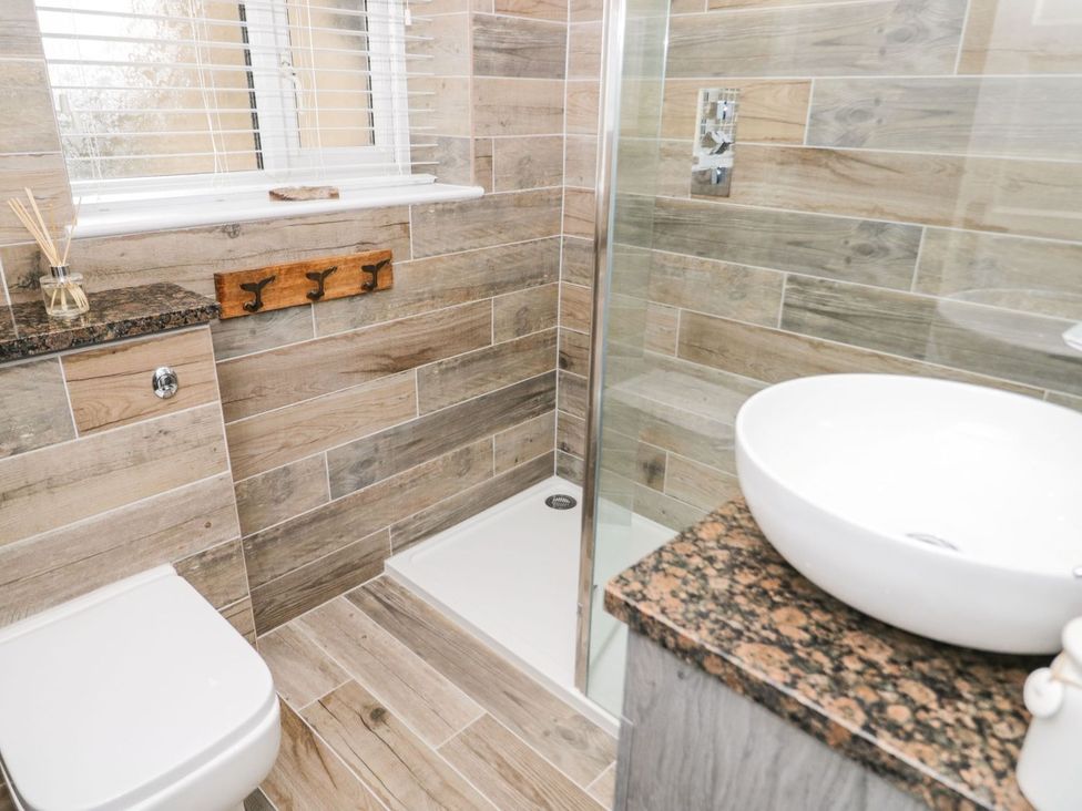 A bathroom with a toilet, shower, and sink at 2 Old Coastguard House Beaumaris