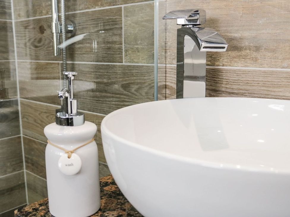 A bathroom sink with a faucet and soap dispenser at 2 Old Coastguard House Beaumaris