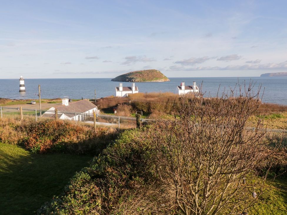 A view of a lighthouse and houses by the sea at 2 Old Coastguard House in Beaumaris