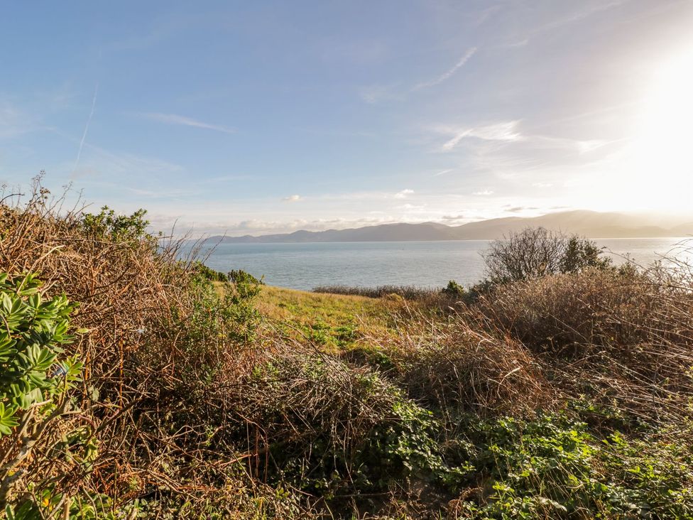 A view of the sea with grass and bushes at 2 Old Coastguard House Beaumaris
