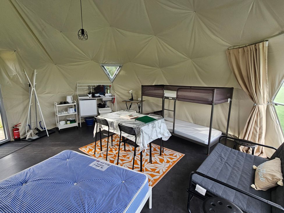 An indoor living space with beds and kitchen unit at Sherwood - Geodome in Mansfield