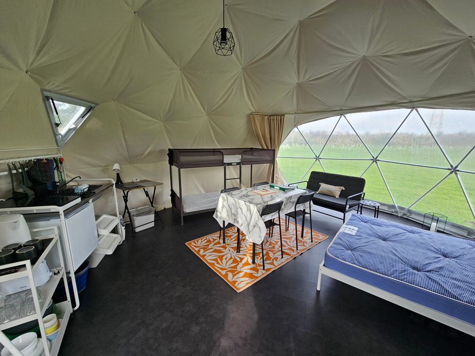 A geodome interior with a dining table, sofa, and kitchenette at Sherwood - Geodome, Mansfield