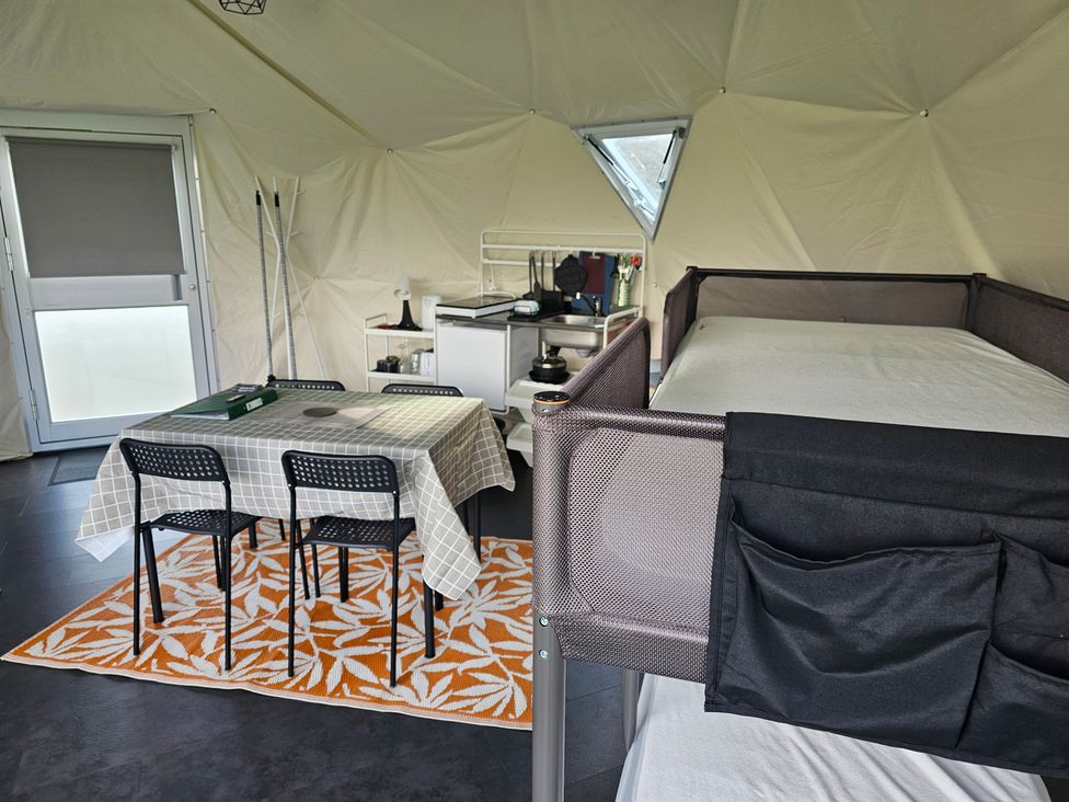 A geodome interior with a table and chairs, kitchenette, and bed at Sherwood - Geodome, Mansfield