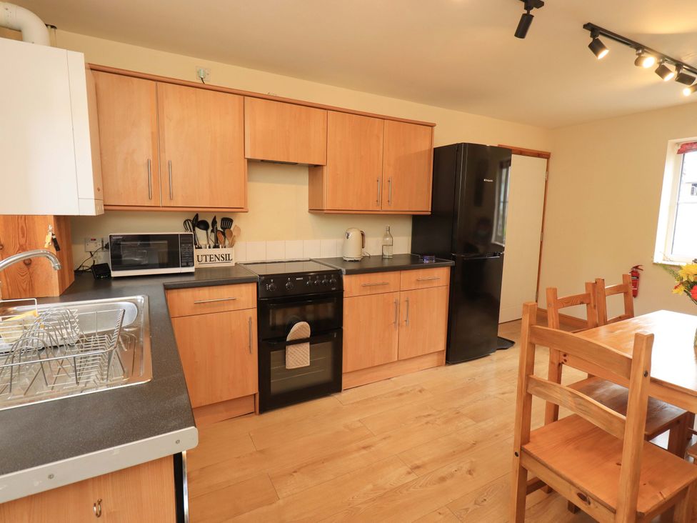 A kitchen with stove, sink, microwave, and table at 4 Mellbecks Mews Kirkby Stephen