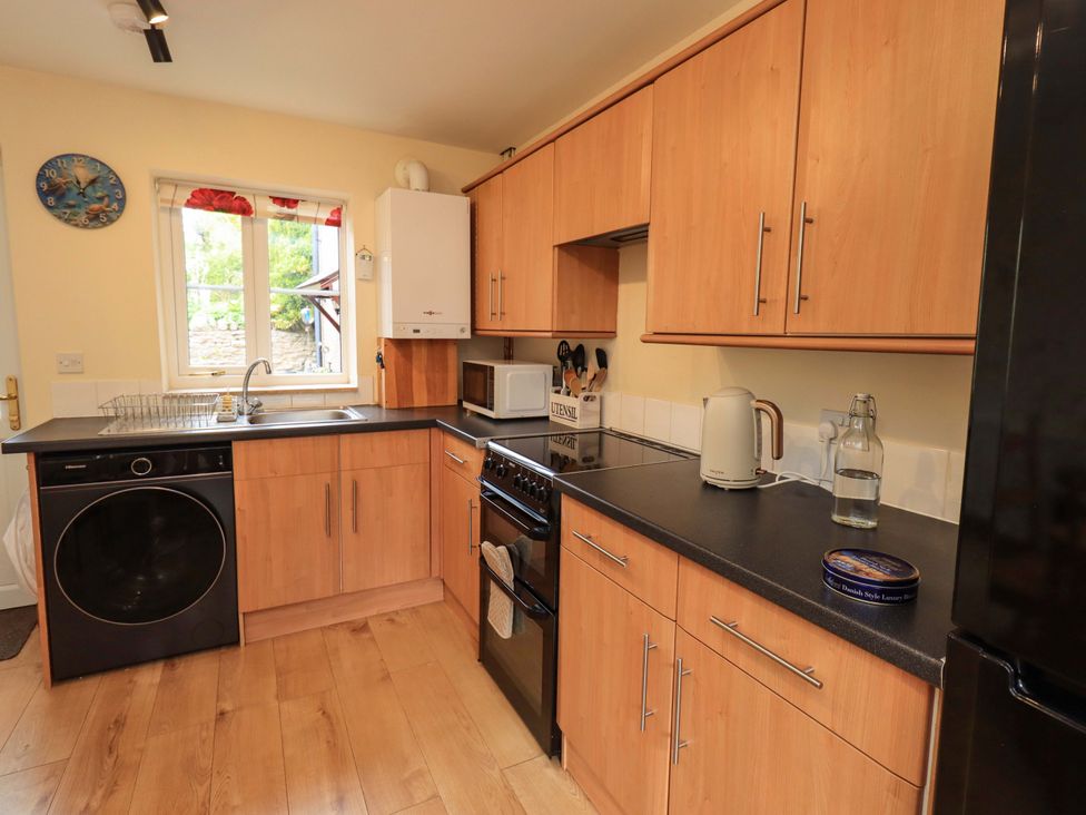 A kitchen with appliances and wooden cabinetry at 4 Mellbecks Mews Kirkby Stephen