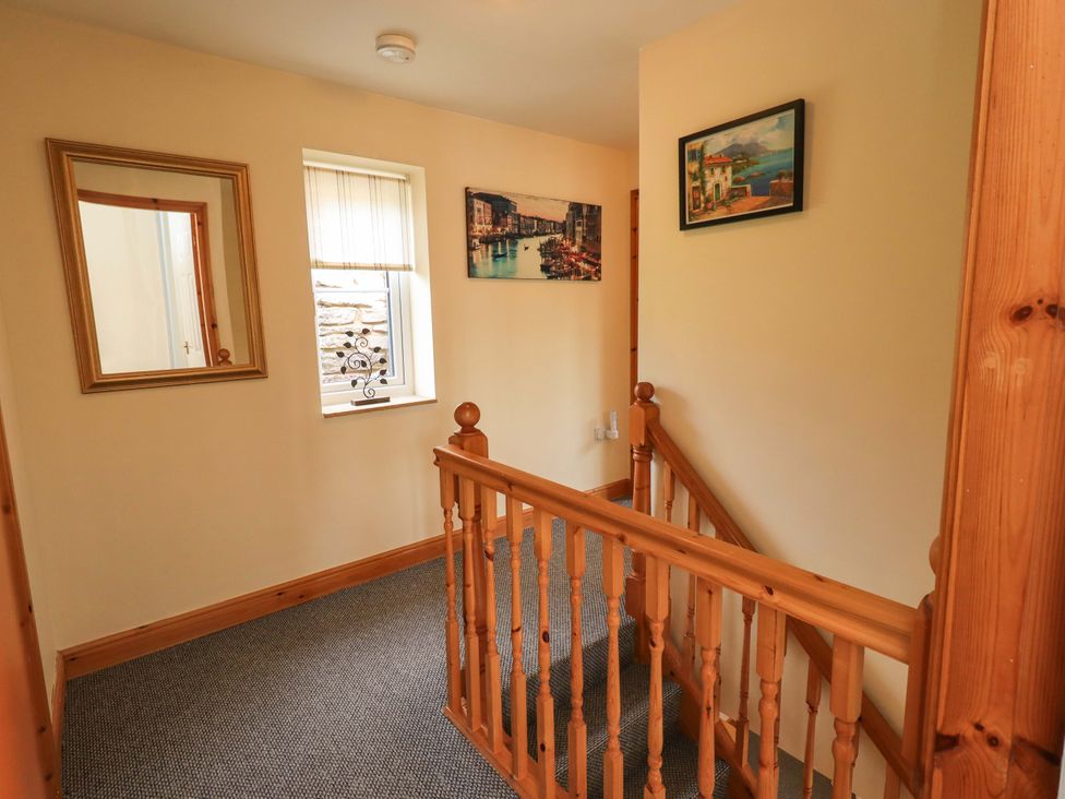 A hallway with a mirror, window, and pictures at 4 Mellbecks Mews Kirkby Stephen