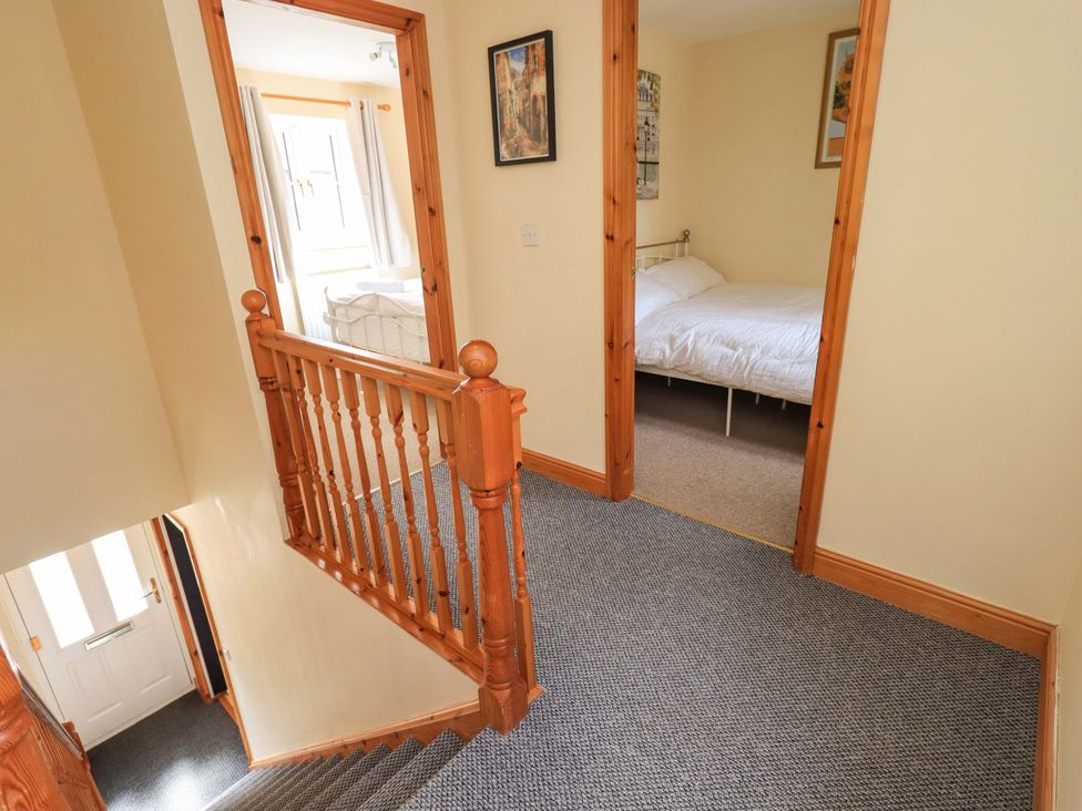 A hallway with a staircase and doors to a bedroom at 4 Mellbecks Mews Kirkby Stephen
