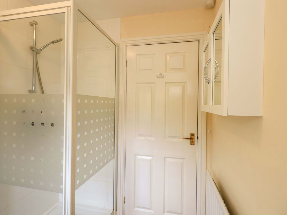 A bathroom with a shower and a door at 4 Mellbecks Mews in Kirkby Stephen