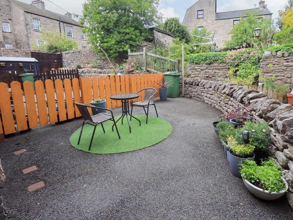 A garden with a table and chairs and planters at 4 Mellbecks Mews Kirkby Stephen