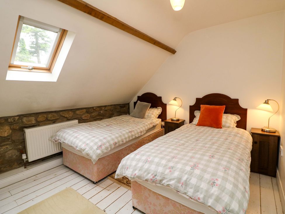 A bedroom with twin beds and bedside tables at Childwall Cottage TULLOGHER