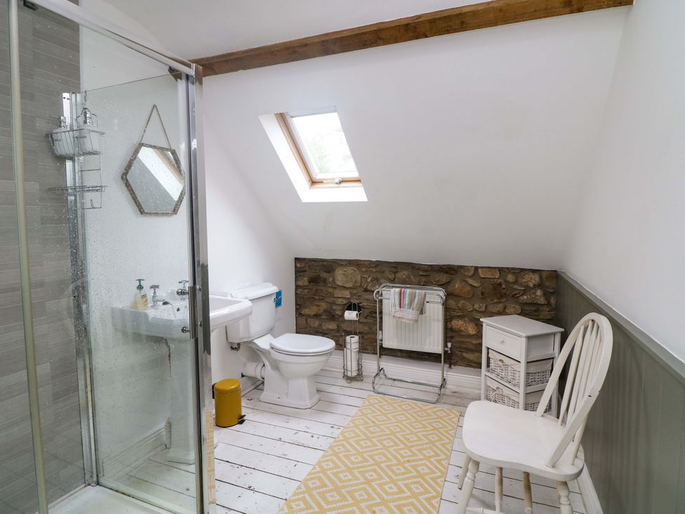 A bathroom with a shower, toilet, sink and a chair at Childwall Cottage TULLOGHER