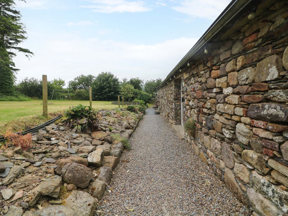 An outdoor path beside a stone wall and grassy area at Childwall Cottage TULLOGHER