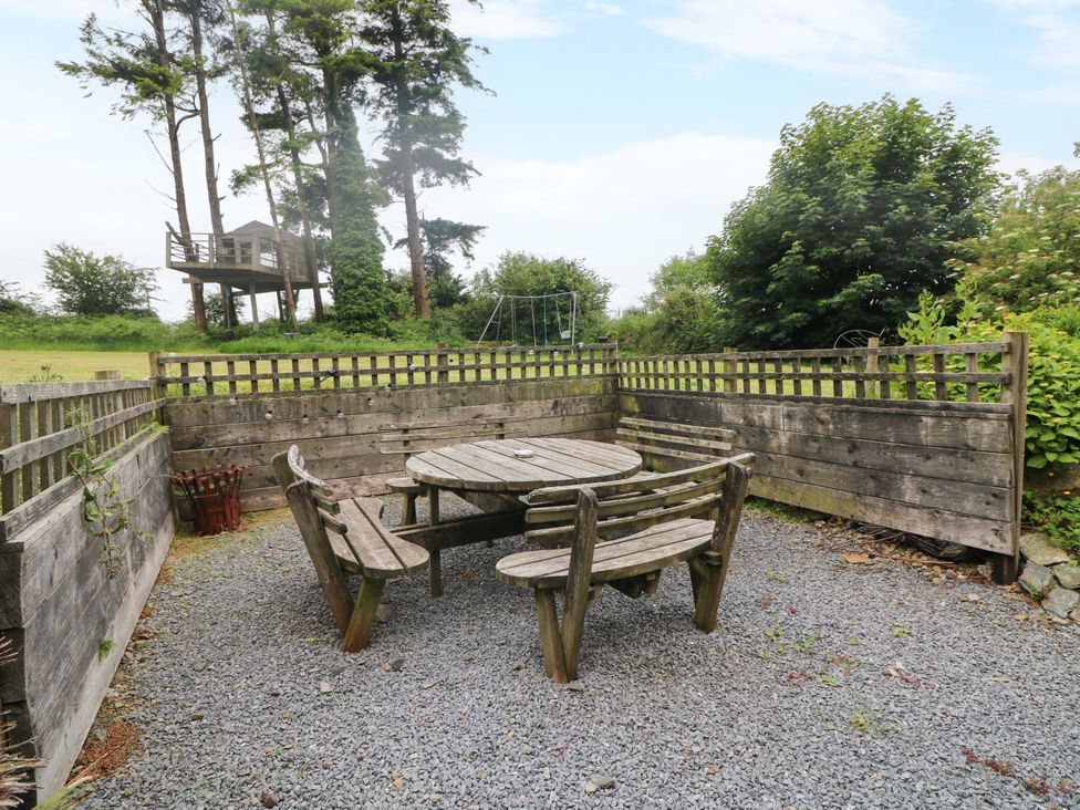 A garden with a wooden table and chairs surrounded by a fence at Childwall Cottage TULLOGHER
