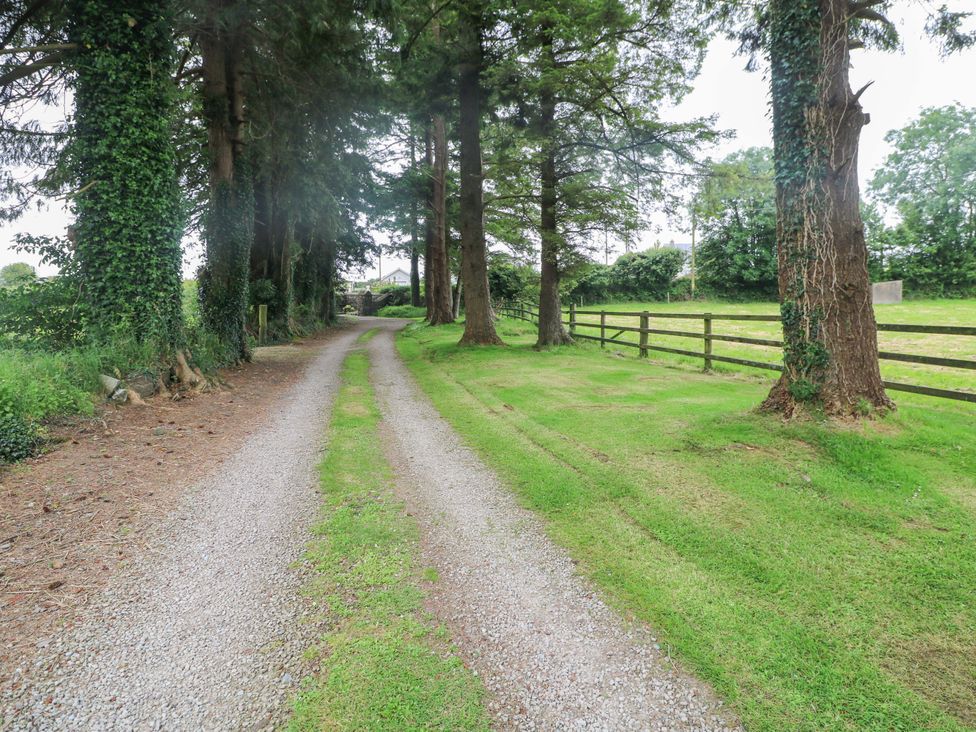 A gravel driveway bordered by trees at Childwall Cottage TULLOGHER
