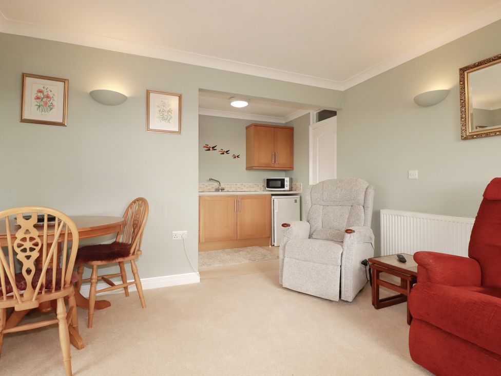A living room with a dining area and kitchen counter at Honeysuckle Rise in Looe