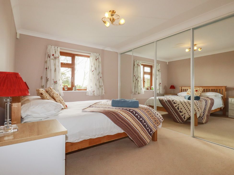 A bedroom with a bed and mirror at Honeysuckle Rise in Looe